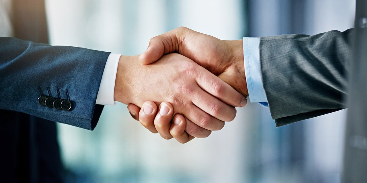 Two men wearing suits shaking hands.